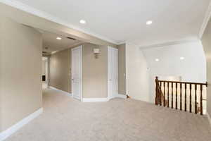 Empty room with crown molding, recessed lighting, and light colored carpet
