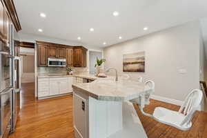 Kitchen with backsplash, light wood-type flooring, recessed lighting, a kitchen bar, and a peninsula