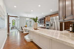 Kitchen with recessed lighting, light stone counters, decorative light fixtures, stainless steel appliances, and light wood-style flooring