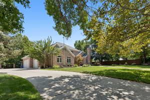 View of front of home with concrete driveway, a chimney, brick siding, and an attached garage