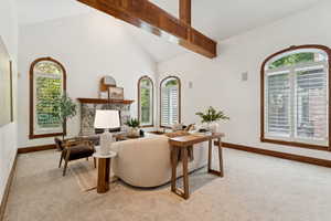 Living area with plenty of natural light, light carpet, a fireplace, beam ceiling, and high vaulted ceiling