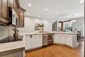 Kitchen featuring light countertops, recessed lighting, light wood finished floors, stainless steel appliances, and hanging light fixtures