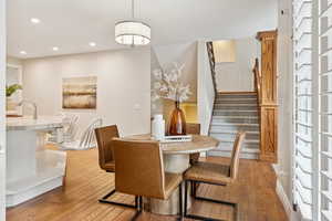 Dining space with light wood finished floors, recessed lighting, and stairs