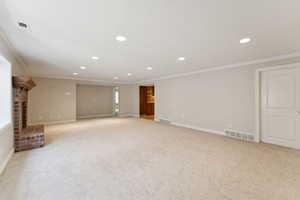 Below grade area with recessed lighting, crown molding, light colored carpet, plenty of natural light, and a fireplace