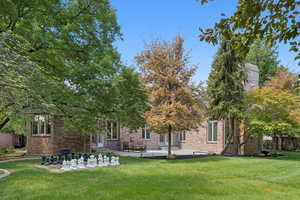 Back of property featuring a lawn, a patio, and brick siding