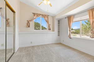 Unfurnished bedroom featuring a closet, carpet, lofted ceiling, and a ceiling fan