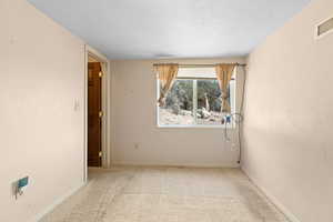 Carpeted empty room with baseboards and a textured ceiling