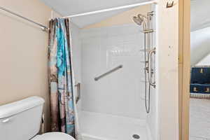 Bathroom featuring a stall shower and lofted ceiling