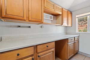 Kitchen with light countertops, light tile patterned flooring, brown cabinets, and a textured ceiling