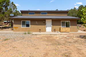 View of front of house featuring stucco siding and a metal roof