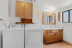 Laundry area featuring a textured ceiling, light tile patterned floors, and washer and clothes dryer