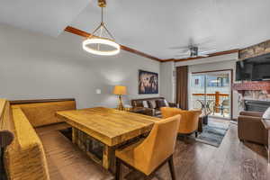 Dining space with dark wood finished floors, a textured ceiling, a fireplace, ceiling fan, and crown molding