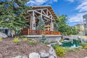 Back of house featuring a wooden deck, stone siding, and a garden pond