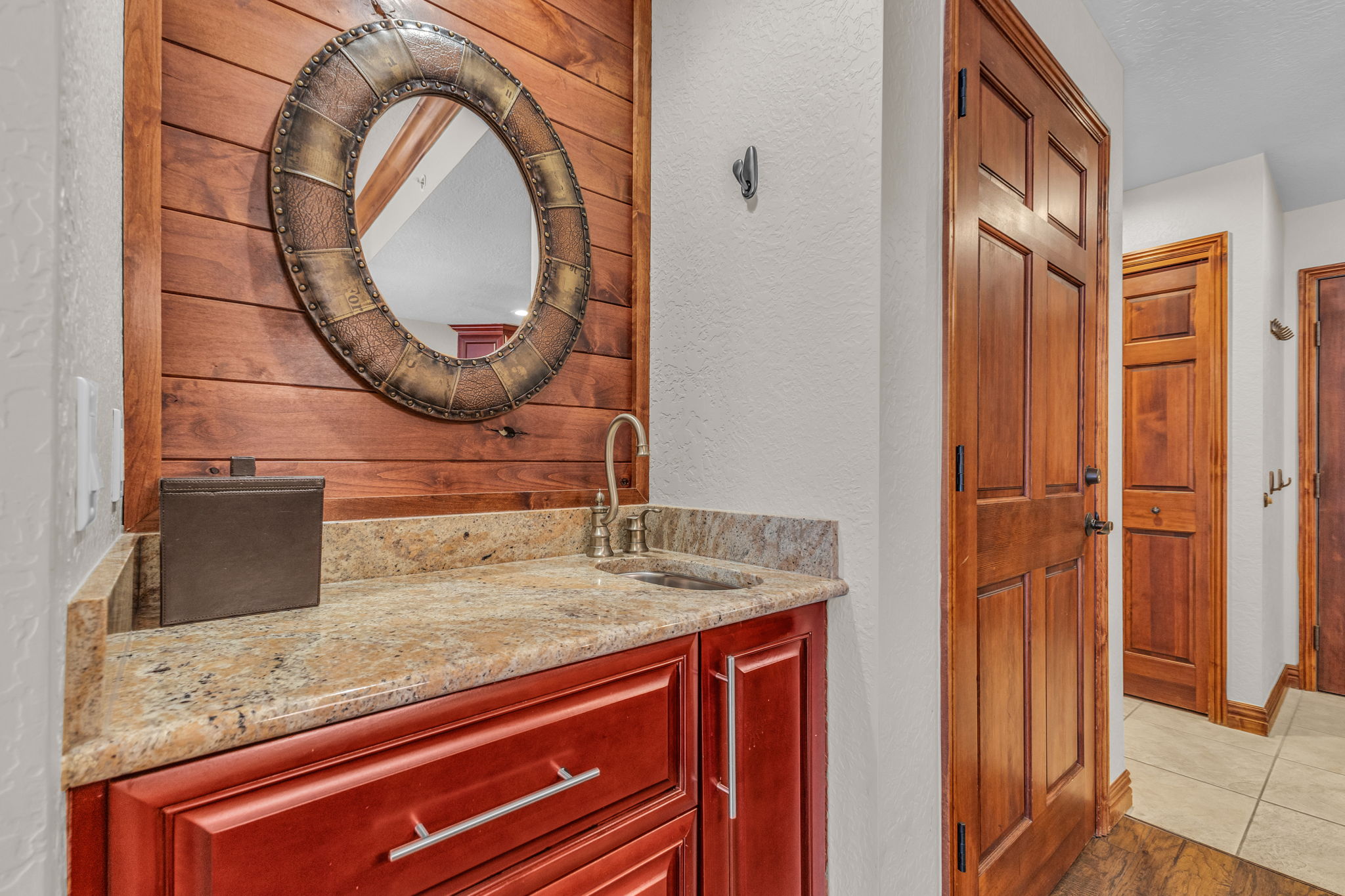 Bathroom with vanity, a textured wall, wood walls, and light tile patterned floors