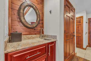 Bathroom with vanity, a textured wall, wood walls, and light tile patterned floors