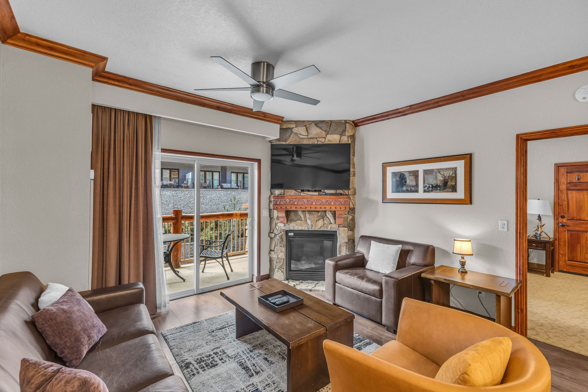 Living area featuring crown molding, a fireplace, wood finished floors, ceiling fan, and a textured ceiling