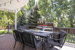 Deck featuring outdoor dining space, a fenced backyard, and view of wooded area