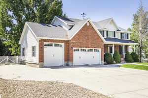Traditional home featuring a garage, driveway, a porch, brick siding, and a shingled roof