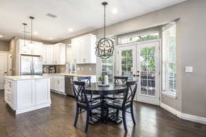Dining room with a chandelier, dark wood finished floors, french doors, and recessed lighting