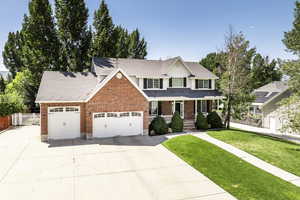 Traditional home with a porch, a garage, concrete driveway, and brick siding