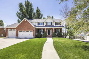 Traditional-style house featuring a porch, an attached garage, brick siding, a front yard, and concrete driveway