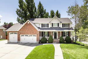Traditional home featuring a garage, a front yard, covered porch, and driveway
