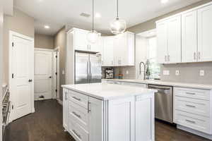 Kitchen with appliances with stainless steel finishes, white cabinetry, dark wood-style flooring, hanging light fixtures, and recessed lighting