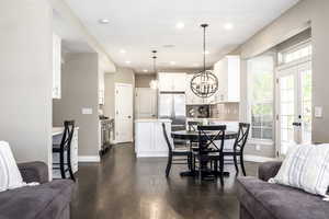 Dining space with dark wood-type flooring, a chandelier, recessed lighting, and french doors