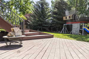 Wooden terrace featuring a playground and stairway