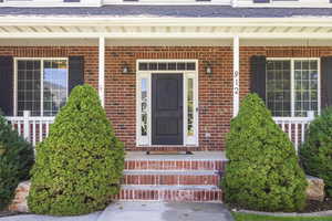 Doorway to property featuring covered porch and brick siding