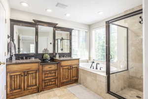 Bathroom featuring a stall shower, plenty of natural light, a bath, double vanity, and recessed lighting
