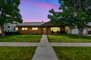 Ranch-style home featuring a metal roof, a yard, garage, shop, and covered porch.