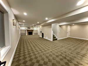 Finished below grade area with recessed lighting, a fireplace, stairway, carpet, and built in features