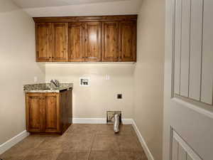 Laundry area featuring hookup for a washing machine, dark tile patterned floors, cabinet space, and electric dryer hookup