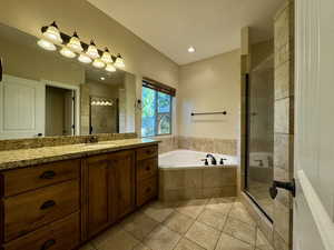 Bathroom with a stall shower, vanity, a bath, light tile patterned floors, and recessed lighting