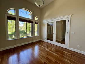 Empty room featuring french doors, wood finished floors, and a towering ceiling