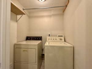 Laundry room featuring tile patterned floors, washer and clothes dryer, and a textured ceiling