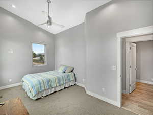 Bedroom with vaulted ceiling, ceiling fan, and light colored carpet
