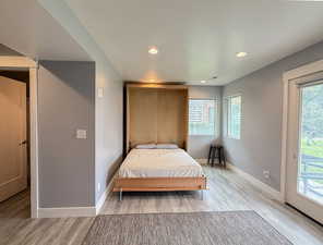 Bedroom with access to exterior, light wood finished floors, recessed lighting, and multiple windows