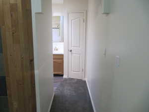 Hallway with baseboards and dark carpet