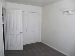Unfurnished bedroom featuring dark colored carpet and a closet