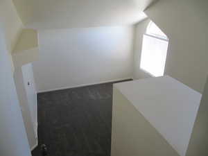 Bonus room featuring vaulted ceiling and dark carpet