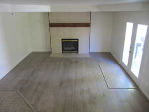 Unfurnished living room featuring a tile fireplace, wood finished floors, and french doors
