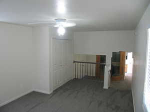 Spare room with dark colored carpet and a ceiling fan