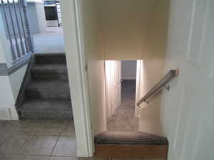 Staircase with carpet floors and tile patterned floors