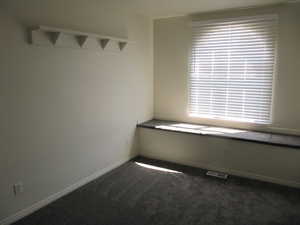 Empty room featuring dark carpet and baseboards