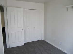 Unfurnished bedroom featuring dark colored carpet and a closet
