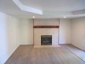 Unfurnished living room featuring recessed lighting, wood finished floors, and a tile fireplace