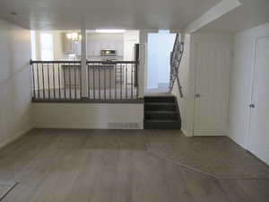 Spare room featuring dark wood-type flooring, a chandelier, and stairs