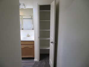 Full bath with vanity, a shower with shower door, dark wood-type flooring, and a walk in closet